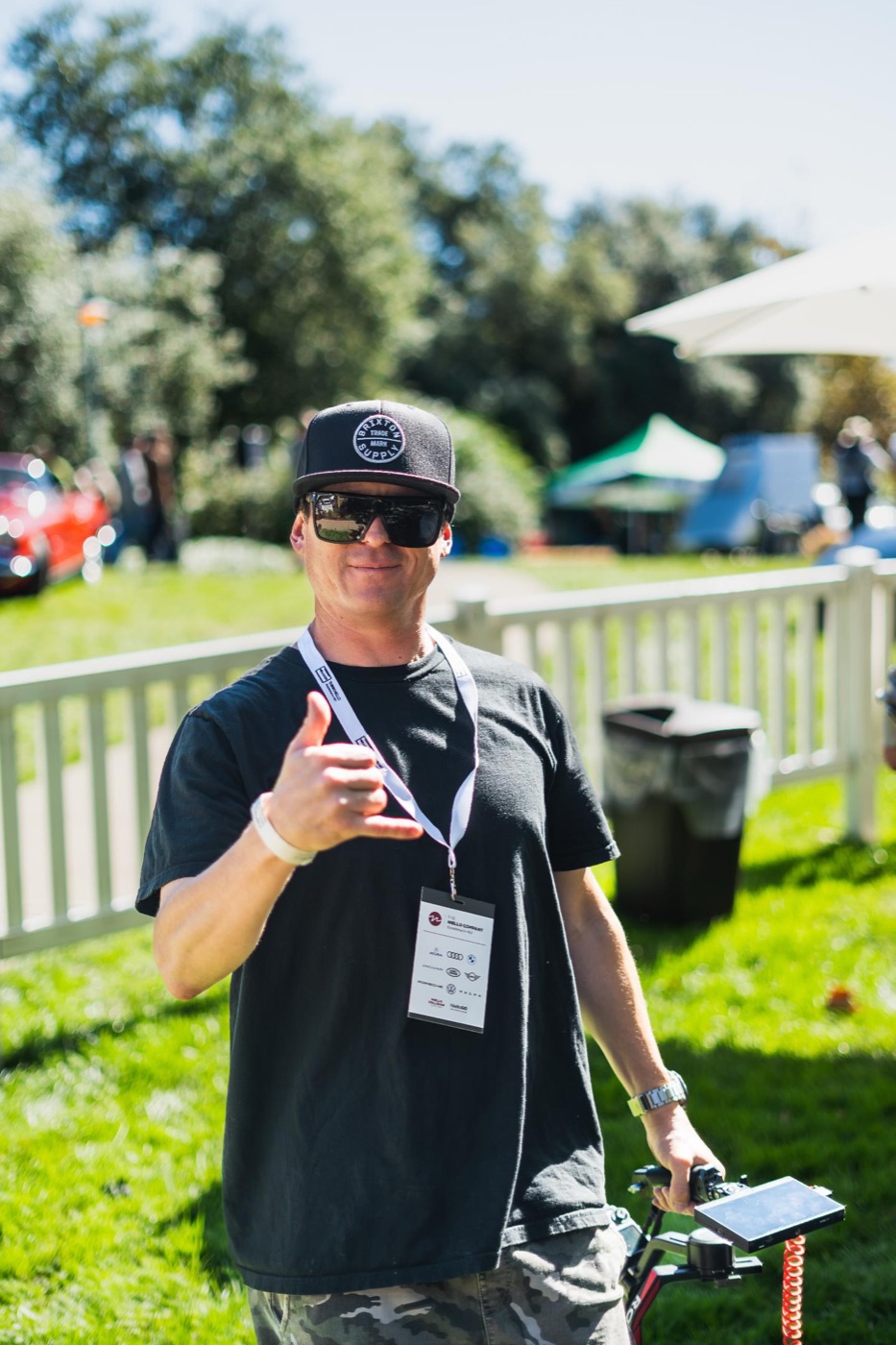 C4Shootz photographer trackside at a car show, giving a shaka while operating a camera gimbal